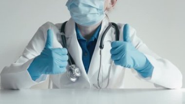 Laboratuvar önlüğü, steteskop, maske ve eldiven giyen kendinden emin bir tıp uzmanı, klinik veya hastane ortamında çifte onay, taşıma güvencesi, pozitiflik ve güvenlik verir..