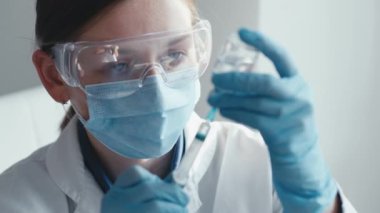 Koruyucu ekipmanlı bir sağlık çalışanı aşı enjeksiyonu hazırlıyor, sağlık, tıbbi içerik, aşı kampanyaları ve laboratuvar ayarları için uygun. Anahtar sözcükler antiviral, biyomedikal, biyoteknoloji, bakım
