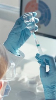 Laboratuvarın içinde, laboratuvar önlüklü bir bilim adamı monitördeki verileri incelerken sıvıyı test tüplerine aktarmak için dikkatlice bir pipet kullanır. Sahne, kesin bilimsel keşifleri tasvir ediyor.