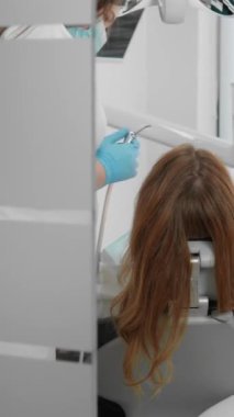 Modern bir klinikte, yetenekli bir dişçi ve asistanı, genç bir hastaya hem rahatlık hem de mükemmel bir tedavi imkanı sunar.