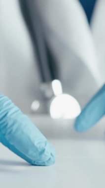 Laboratuvar ortamında, mavi eldiven ve beyaz önlük giymiş, elinde ilaç kapsülü tutan bir sağlık uzmanı. Klinik bir ortamda tedavi ve bilimsel araştırmalara odaklanın.