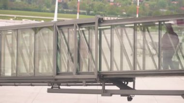 Çağdaş bir terminaldeki bir havaalanı jet köprüsü yolcuların uçağa girmesi için korunaklı bir yol sunmaktadır. Havalimanı deneyimini artırmak için pistin manzarasını sağlayan cam bir cephesi var.