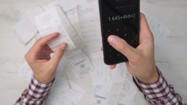 Bir kişi, harcamaları yönetmek, kişisel finansman, bütçe izleme ve gider takibi üzerine odaklanmak, finansal yönetimin önemini göstermek için akıllı telefon üzerinde bir hesap makinesi uygulaması kullanıyor