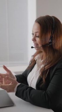 Çağdaş bir ofis ortamında, kendine güvenen bir iş kadını, kulaklıklı, profosyonel bir görüntü sunan ve takımı için olumlu bir çalışma ortamı yaratan, üretken bir çevrimiçi toplantıya liderlik ediyor.