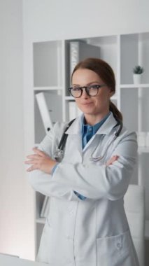 Modern bir muayenehanede steteskop ve gözlük takan kendine güvenen bir kadın doktor. Sağlık alanında bulunan özveri ve özveriyi somutlaştırarak profesyonellik ve uzmanlık sergiliyor..