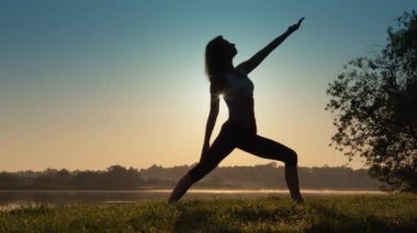 Her yaştaki kadınlar için doğal bir ortamda rahatlama ve iyileşme. Nehrin kıyısında yoga yapmak denge ve uyum sağlamaya, sakin ve odaklanmış hissetmeye yardımcı olur. Yüksek kalite 4k görüntü