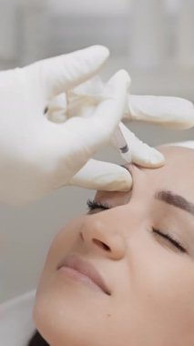 Klinik ortamda, bir kadın güzellik geliştirmek için belirli tekniklerle yüz enjeksiyonundan geçer, profesyonel bir ortamda modern güzellik tedavileri ve cilt bakımı gösterir.