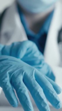 Mavi eldiven ve laboratuvar önlüğü giyen bir sağlık uzmanının odaklanmış bir görüntüde prosedüre hazırlandığı görülüyor. Sağlık ve profesyonellikle ilgili konular için uygundur