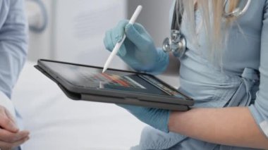 Eldiven ve steteskop giyen bir sağlık uzmanı hasta kayıtları veya tıbbi veri girişi için stili olan dijital tablet kullanır. Bu etkileşim hastane ya da klinik ortamında gerçekleşir.