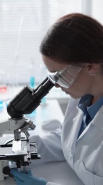 Kendini adamış bir bilim adamı modern bir laboratuvarda mikroskop kullanarak araştırma yapıyor. Bu görüntü, profesyonel bir laboratuvar ortamında bilimsel araştırmanın ve ilerlemenin özünü yakalar..