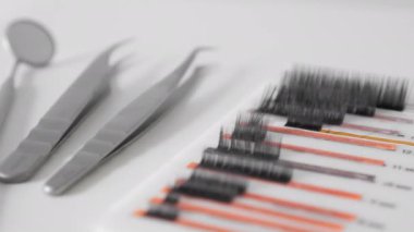 Kirpik uygulaması için güzellik salonlarında kullanılan profesyonel kirpik uzantılarını ve titiz cımbızları ön plana çıkaran yüksek kaliteli yakın çekim görüntüleri. Güzellik, makyaj veya kuaförle ilgili içerik için mükemmel.