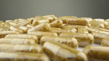 Şeffaf kapsüller ve beyaz zemin üzerinde yavaşça dönen besin maddeleri. Sağlığa ve tedaviye ulaşmak için ideal bir yol. Yüksek kalite 4k görüntü