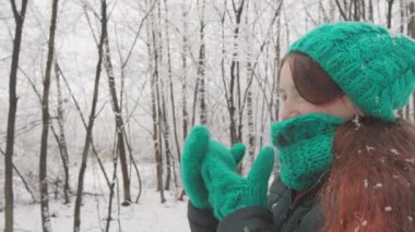 Yeşil örgü şapkalı, atkılı bir kadın soğuk ağaçların arasında kışın harikalar diyarına dalmış karlı bir günün tadını çıkarıyor. Macera, rahat, karlı orman, kış ıssızlığı