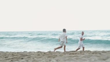 Sadık bir baba ve neşeli genç oğlu kumlu sahilde oynuyorlar, aktivitelerden keyif alıyorlar, denizin güzelliğine dalmış, ve sıcak güneş ışınlarının altında kalıcı anılar yaratıyorlar.