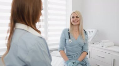 Modern bir tıbbi ortamda, kadın bir doktor steteskopla bir hastayla sıcak bir ilişki kurar, rahat bir ortam sağlar, pozitif bir doktor hasta ilişkisini temsil eder.