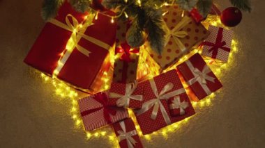 Parlak kurdelelerle süslenmiş renkli Noel hediyelerinin ışıldayan ışıklarla parıldayan muhteşem bir ağacın altına yerleştirilmiş neşeli tatil ruhunun gerçek özünü yansıtan canlı bir sahne.