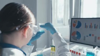 Koruyucu giysi araştırmacısı, biyolojik bir örneği analiz eder ve yüksek teknolojili bir ekranda verileri izler, modern bilimsel uygulamaları göstererek, anlayışı artırır ve yeniliği teşvik eder.