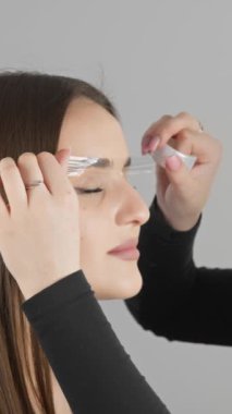 Bir makyaj sanatçısı modern bir güzellik salonundaki müşterisine titizlikle kaş jölesi sürer. Bu profesyonel kozmetik prosedürü müşterilerin doğal kaşlarını, hassasiyetini ve bakımını arttırır..