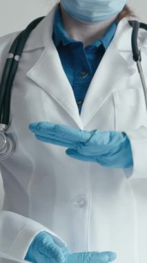 Beyaz laboratuvar önlüğü, steteskop, eldiven ve yüz maskesi giyen bir tıp uzmanı klinik ortamda uygun el hijyeni tekniklerini gösterir. Güvenlik ve temizliğe vurgu.