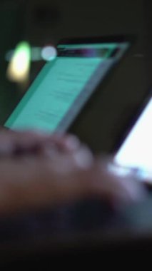 Görüntü, loş ışıklı bir odada iki dizüstü bilgisayarda el yazısını gösteriyor. Ekranlar yumuşak bir şekilde parlıyor. Geceleri programlama ve çoklu görev yapan bireylerin yoğun odak noktalarını yansıtıyor.
