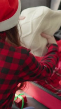 Neşeli şapkalı neşeli bir kadın heyecanlı bir kış tatili için bavulunu sıcak kıyafetlerle dolduruyor. Önümüzdeki mutlu Noel ve yeni yıl kutlamalarını heyecanla bekliyor.