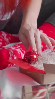 Sıcak bir Noel sahnesi hayal edin, elleri hediyeleri açan, kırmızı süslemelerle çevrili, sıcak bir atmosferde sevdiklerimiz arasındaki sevinçli bayram ruhunu yakalayan.