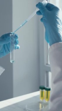 Modern bir laboratuvarda, yetenekli bir bilimadamı deneyler için hassas bir pipet kullanırken, organize ekipmanlarla çevrili büyük bir ekrandaki verileri analiz ederek, araştırmaya güçlü bir bağlılığı yansıtır.