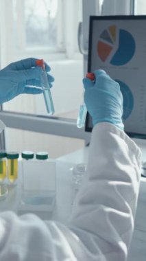 Laboratuvar önlüğü giymiş kendini adamış bir bilimadamı, canlı mavi sıvılarla deneyler yaparken, bir bilgisayardaki verileri analiz ediyor, araştırma ve eğitim için ileri laboratuvar teknikleri sergiliyor.