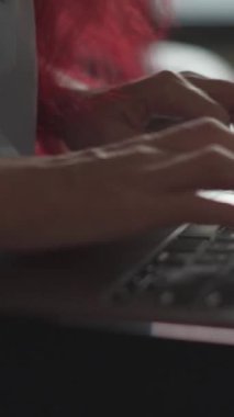 Bu resim, dizüstü bilgisayarda yazı yazan elleri gösteriyor, modern bir çalışma alanındaki yaratıcılığın ve verimliliğin özünü yakalıyor, arka planda canlı bir atmosfere yeni bir saç rengi ekliyor.