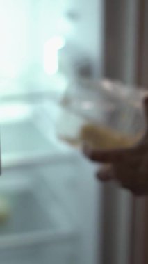 Hafifçe aydınlatılmış ve loş mutfakta bir kadın, gece yemenin sayısız zorluklarını ve bunun sindirim ve beslenme tercihleri üzerindeki önemli etkilerini vurgulayarak, özenle bir yemek hazırlar.