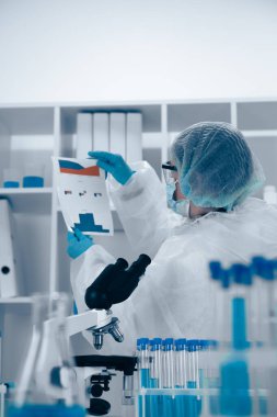 Gelişmiş laboratuvar ekipmanları arasında önemli bir belge üzerinde çalışan kendini adamış bir araştırmacı, bilimsel keşiflere olan bağlılıklarını ve araştırmalarda kapsamlı analizleri vurguladı.