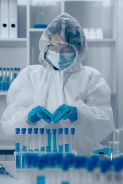 Yüksek teknolojili bir laboratuvarda, koruyucu ekipman içinde kendini adamış bir bilim adamı biyolojik örnekleri titizlikle inceliyor. Bu gayretli çalışma toplumu önemli ölçüde geliştirmeyi ve halk sağlığını iyileştirmeyi amaçlıyor.