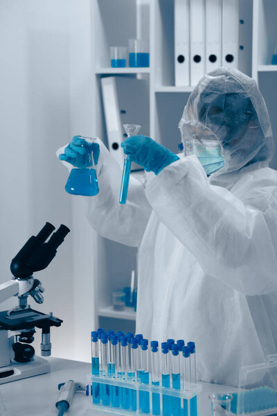 В современной лаборатории самоотверженный исследователь в области защитного оборудования умело манипулирует стеклянной посудой и пробирками, демонстрируя точный и структурированный характер современных научных экспериментов