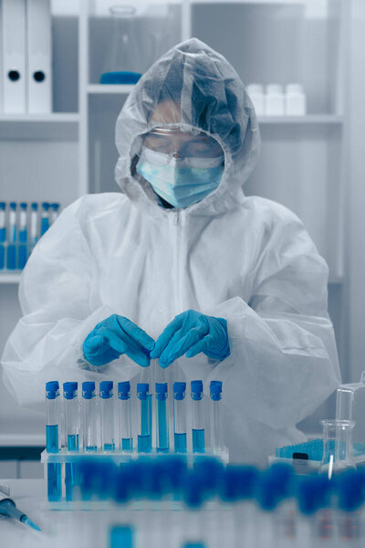 В высокотехнологичной лаборатории ученый в защитном снаряжении с точностью исследует биологические образцы. Эта кропотливая работа направлена на значительное развитие общества и улучшение общественного здравоохранения.