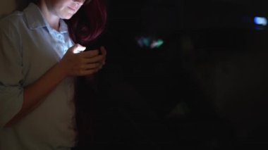 Genç bir kadın, dijital çevresindeki dikkat dağıtıcı şeylerle maskelenmiş, derin yalnızlığının altını çizerek modern bağlantıyı temsil eden akıllı telefonlarıyla parıldıyor.