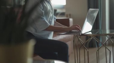 Bir kadın laptopuna derinden odaklanmış rahat ve rahat bir yaşam alanında, üretkenlik duygusu sergiliyor ve ev ortamının davetkar atmosferiyle modern çalışma ortamını temsil ediyor.