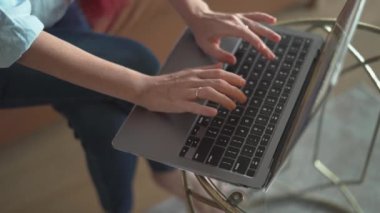 Tamamen odaklanmış bir birey, düzgün, modern bir dizüstü bilgisayara yazarak, serbest ve uzak çalışma görselleri için ideal bir ortam içinde üretkenlik sergiliyor.