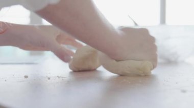Ahşap bir yüzeyde hamur yoğurup ekmek yapma sanatına odaklanan bir birey. Görüntü, ev yapımı ekmeği hazırlama sürecini yakalıyor ve elle yapılan yaklaşımı vurguluyor..