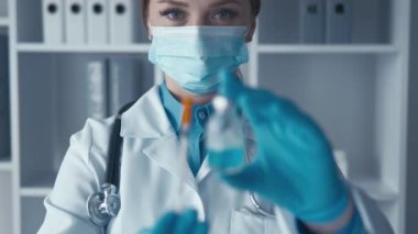 Beyaz laboratuvar önlüğü ve koruyucu eldivenleriyle kendini adamış bir bilim adamı cam bir test tüpünde canlı mavi bir sıvıyı inceliyor ve modern bir laboratuarda yenilikçi bir araştırmaya olan bağlılığını yansıtıyor.