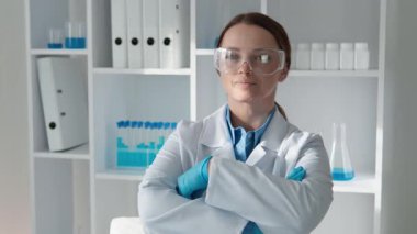 Modern bir laboratuvarda, laboratuvar önlüğü ve gözlüklü kendinden emin bir kadın bilim adamı, deneyler yapmak ve bilimsel araştırmaları ilerletmek için gerekli olan cam eşyalar ve malzemelerle özenle çalışır.