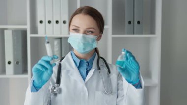 Beyaz önlüklü ve steril eldivenli bir sağlık uzmanı, klinik bir ortamda etkili bir hasta bakımı için hayati önem taşıyan bir şırınga ve şişe bulundurur.