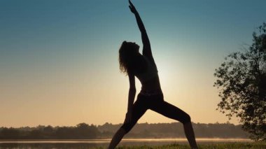 Gün batımında yoga yapan, huzur, ahenk, denge ve huzur dolu bir yaz için hazırlanan büyüleyici bir siluet.