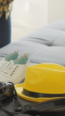 Canlı bir sahne, parlak sarı bir bavul, şık ayakkabılar, şık bir şapka ve önlerindeki keşiflerin heyecan verici maceralarını sembolize eden bir kamera eşliğinde bir gezi için hazırlanmanın zevkini yakalar.