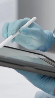 Yetenekli bir sağlık uzmanı hayati tıbbi bilgilere ulaşmak için bir tablet ve stil kullanır, teknolojinin modern hasta bakımı ve sağlık sonuçları üzerindeki etkisini gösterir