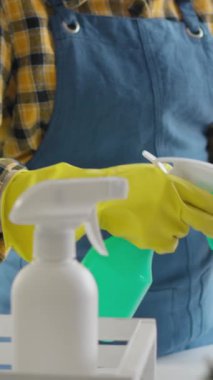 Sadık bir bahçıvan, eldivenli ve önlüklü bir bahçıvan ev bitkilerini nazikçe yeşil bir su şişesiyle besliyor ve bitkilerin sağlığı ve güzelliği için gerekli önemi vurguluyor.