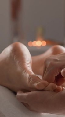 Yumuşak ışıklandırma ve rahatlatıcı bir ortam ile çevrili, son derece sakin bir spa ortamında son derece rahatlatıcı bir ayak masajı gerçekleştiriliyor.