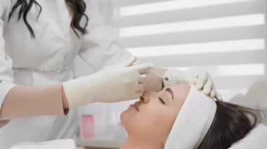 Güzellik kliniğinde yetenekli bir uzman hastaya botulinyum enjeksiyonu yapar. Alnındaki kırışıklıkları hedef alır. Bu cilt bakımında daha düzgün ve daha genç görünmesi için.