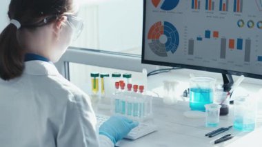 Beyaz önlüklü yetenekli bir araştırmacı, heyecan verici deneyler ve çığır açan bilimsel bulgularla çevrili karmaşık verileri bilgisayarlarında analiz eder.