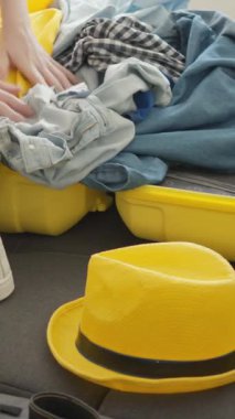 Moda kıyafetlerle dolu canlı sarı bir bavul ve şık bir şapka her yolcunun hissettiği seyahat ve keşif ruhunu somutlaştıran heyecanlı bir tatil beklentisini yakalar.