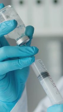 Biyoloji merkezindeki bir laboratuar asistanı örnekleri test ve moleküler analiz için dikkatlice hazırlıyor. Koruyucu eldiven giyen bir kadın elinde kimyasal matara tutuyor. Yüksek